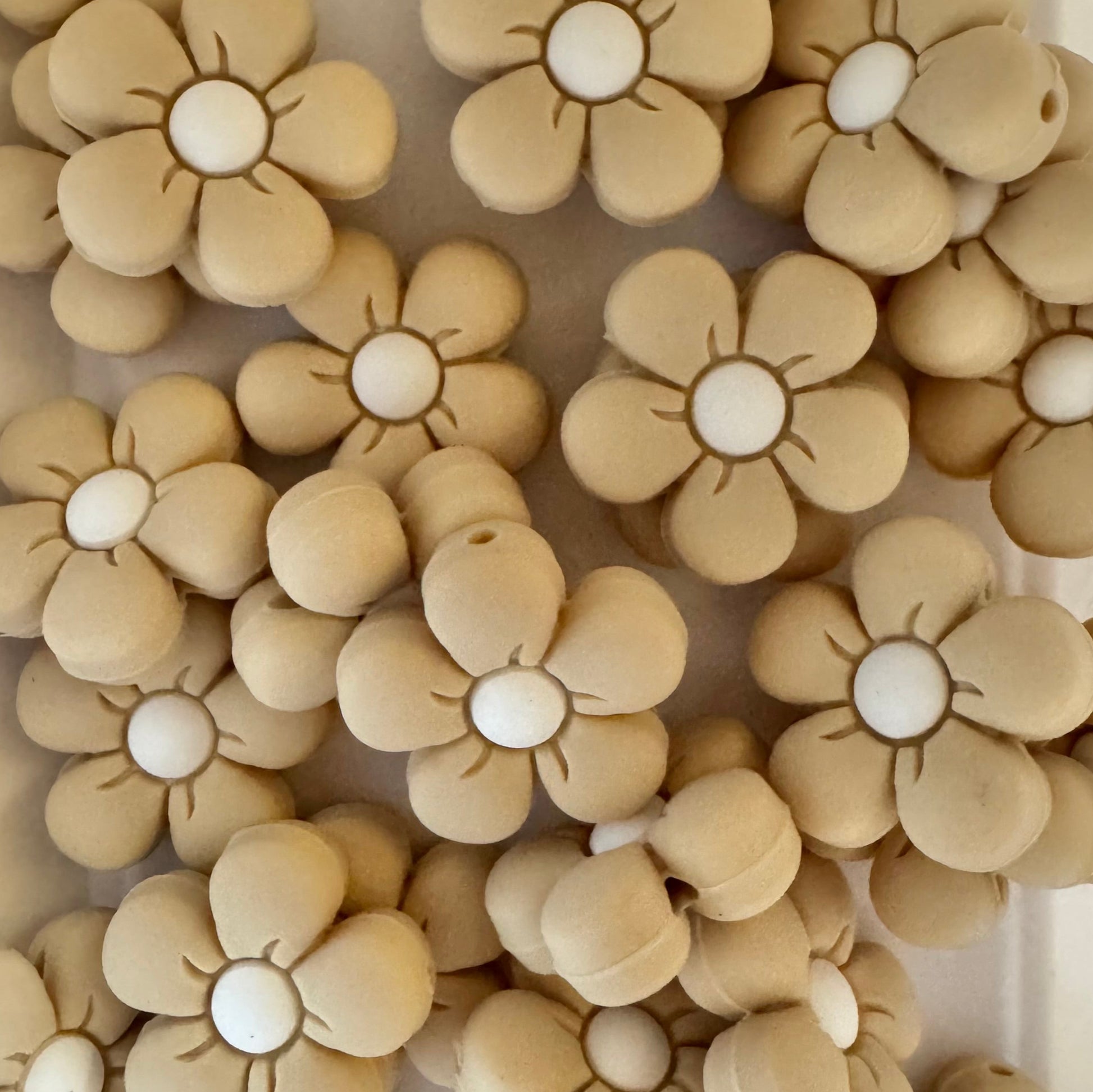 Beige flower-shaped objects with white centers arranged in a pattern on a white background