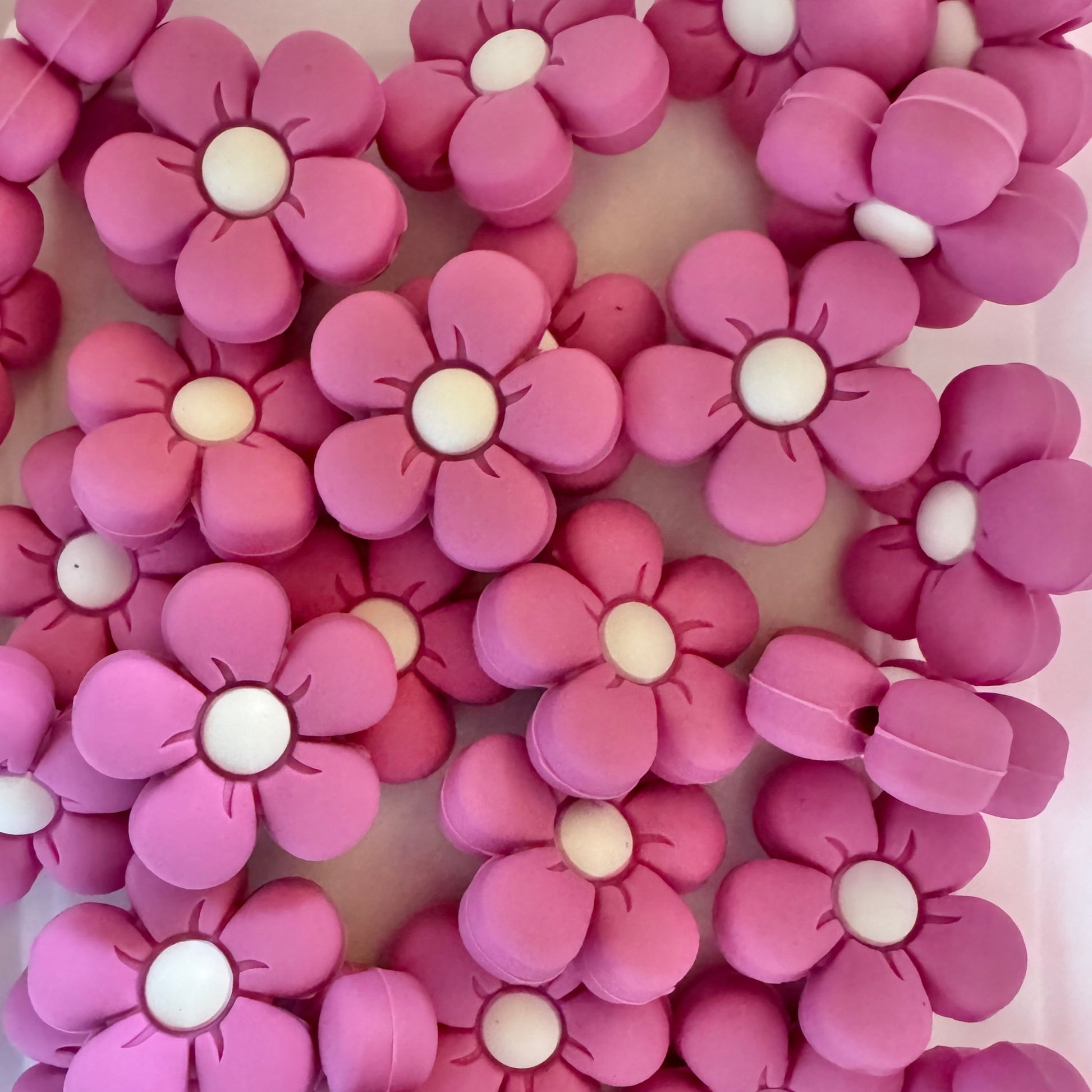 Pink flower-shaped beads with white centers on a white background