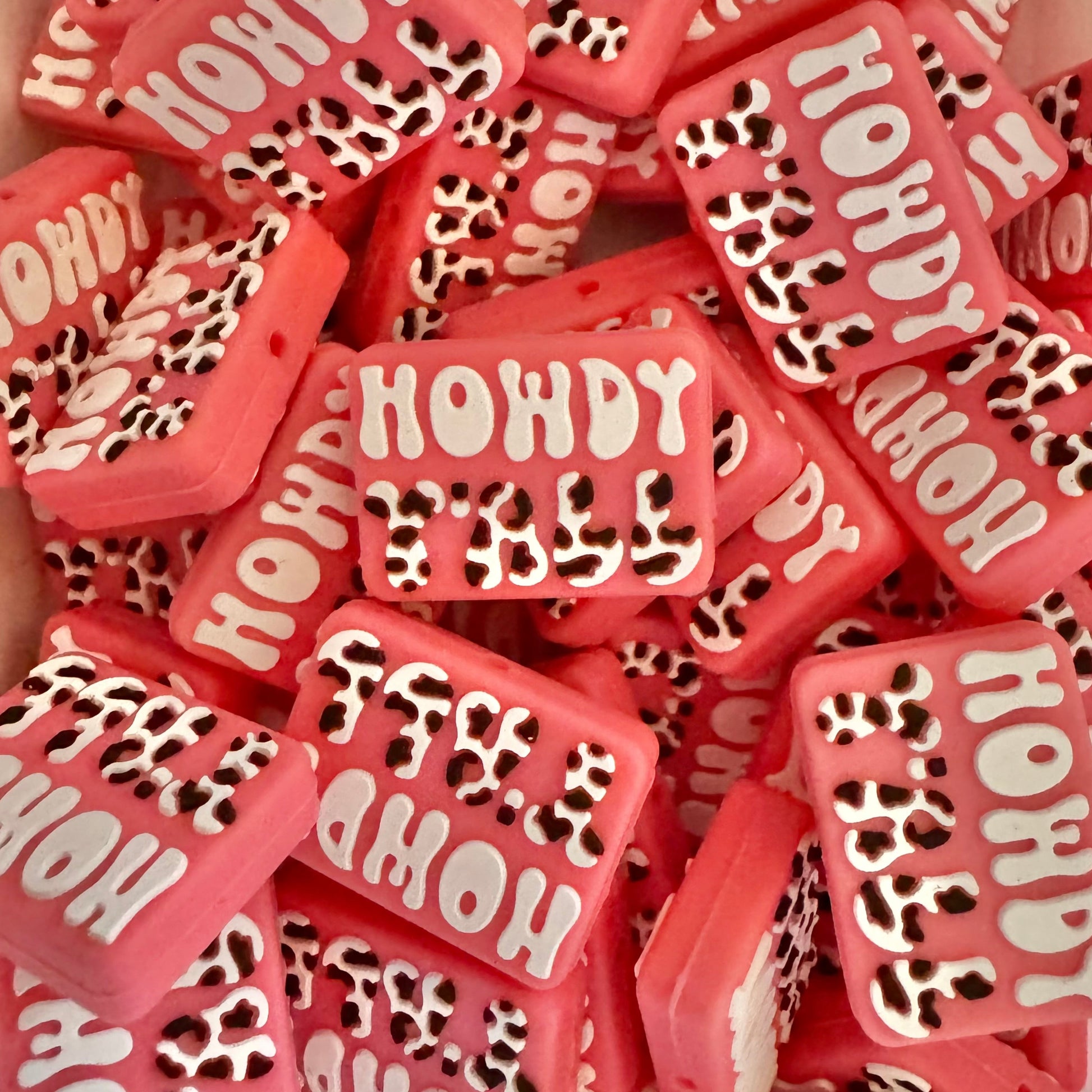Pink and white 'Howdy' beads with leopard print accents on a pink background