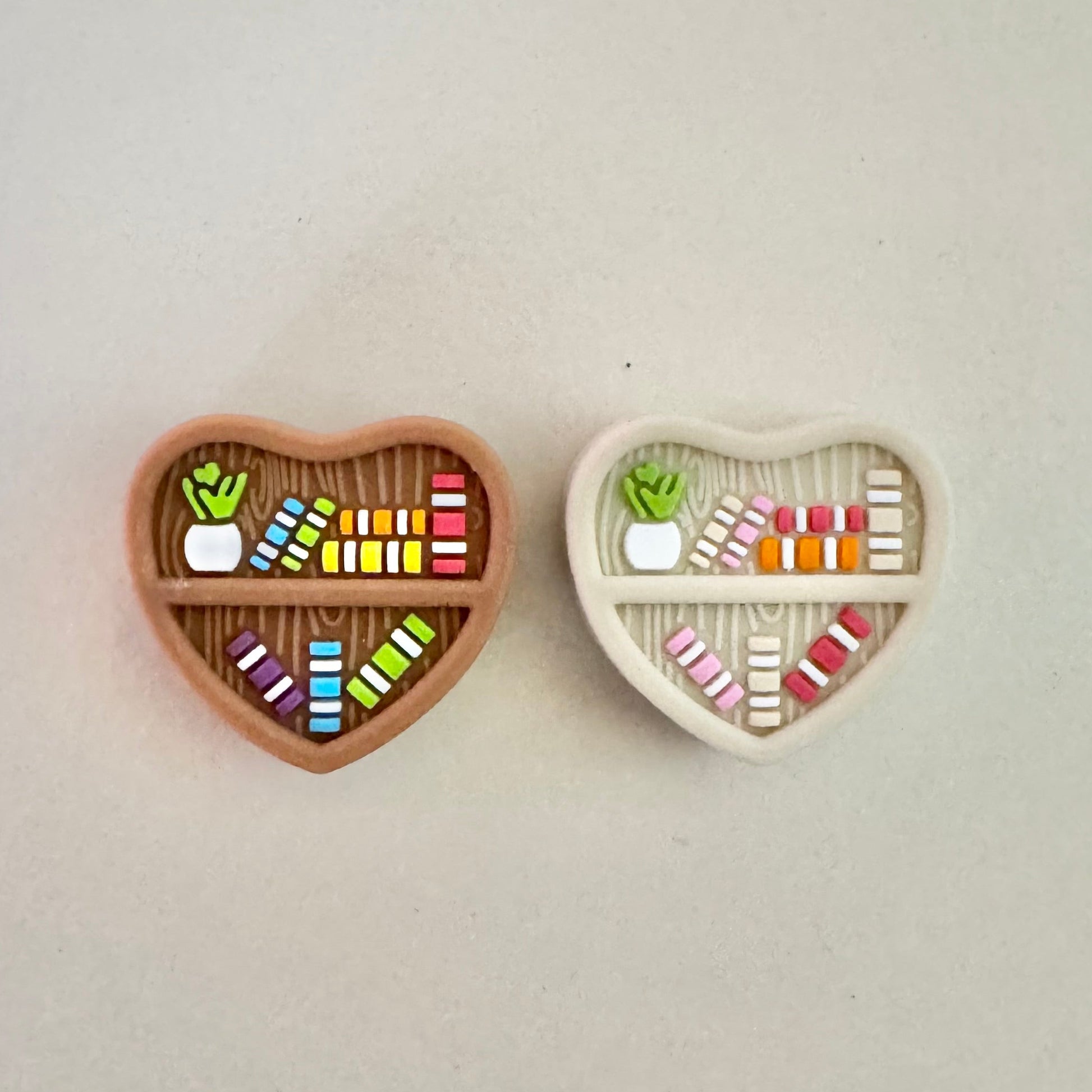 Two heart-shaped containers with colorful items on a light gray background