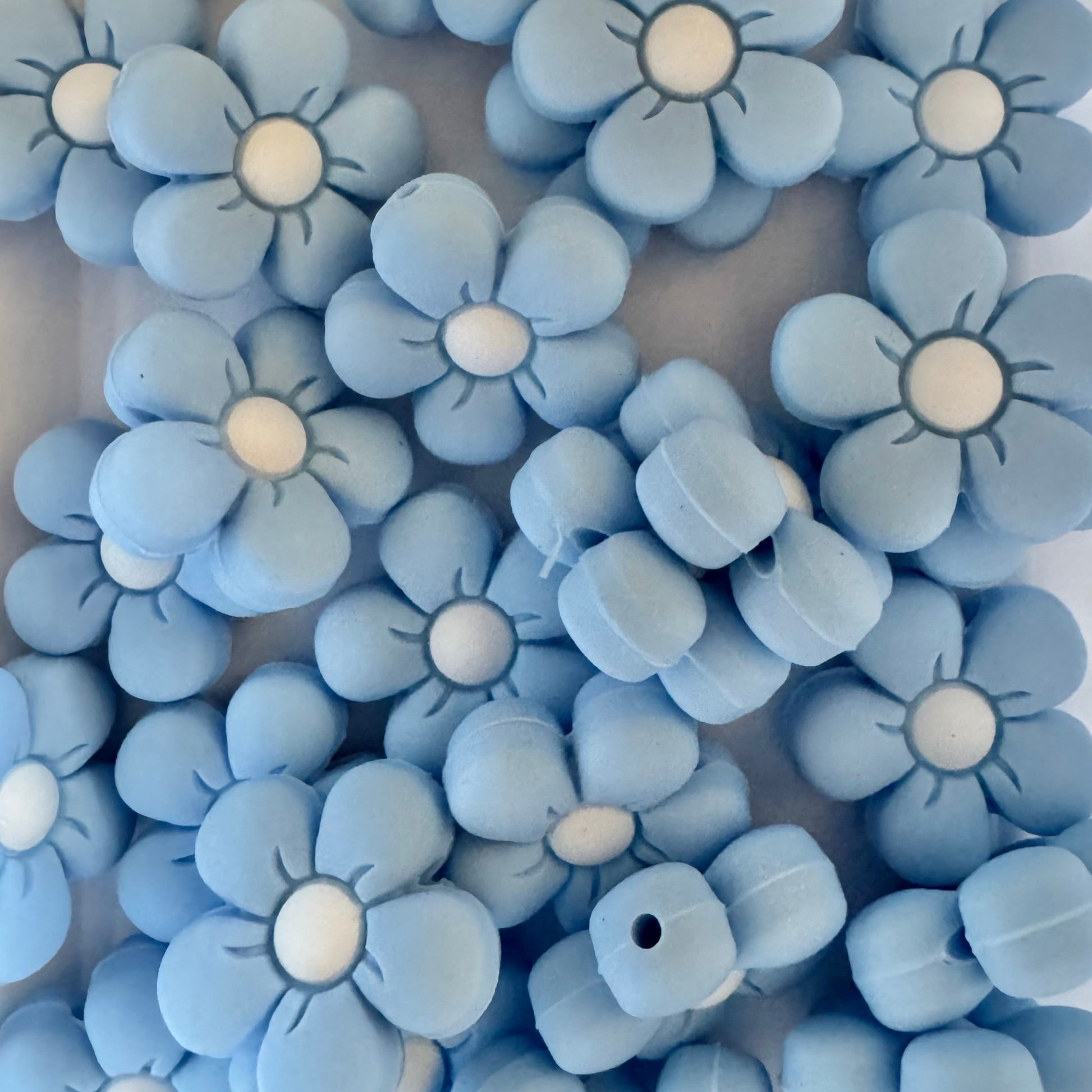 Blue flower-shaped beads with white centers on a white background
