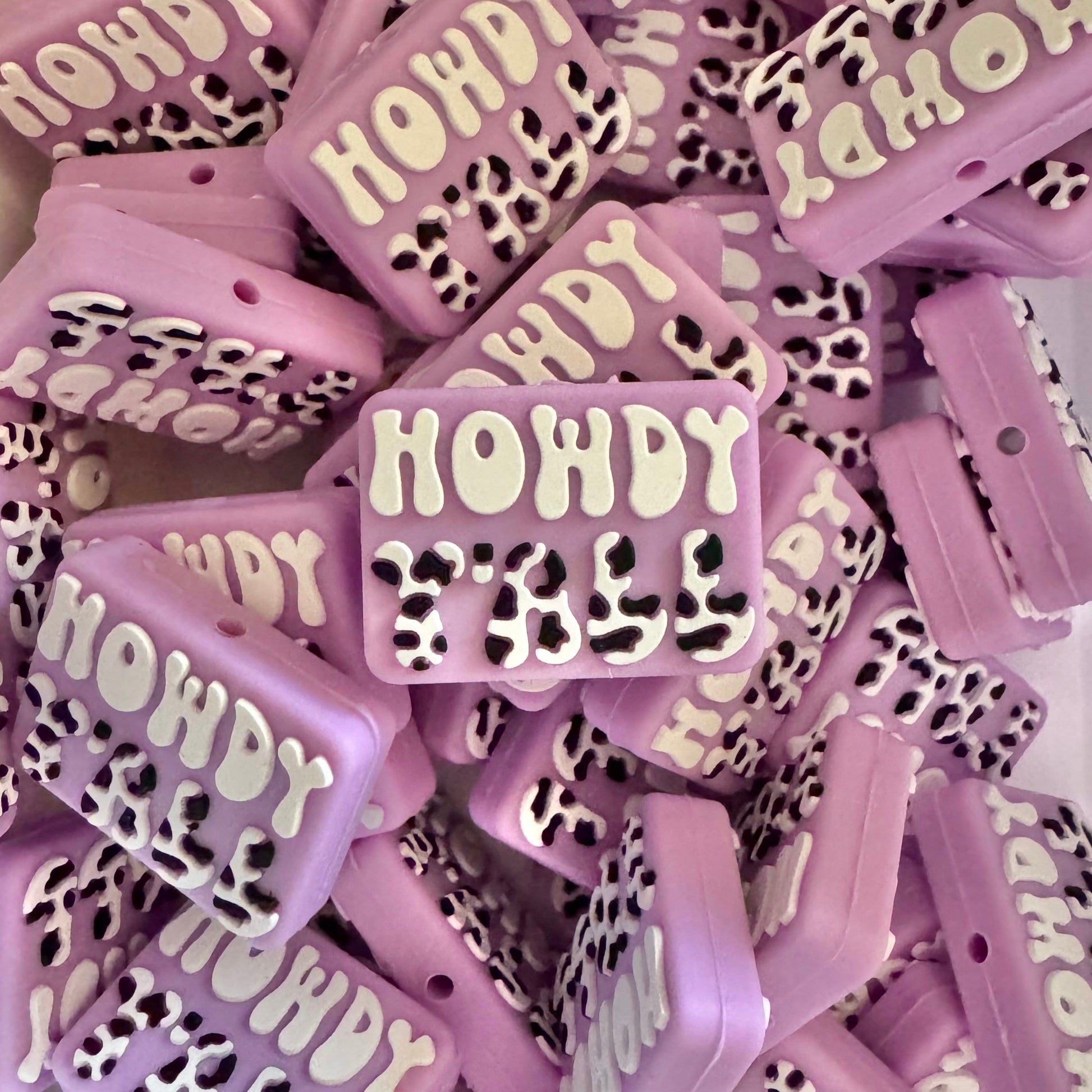 Purple and white 'HOWDY' beads with leopard print accents on a white background