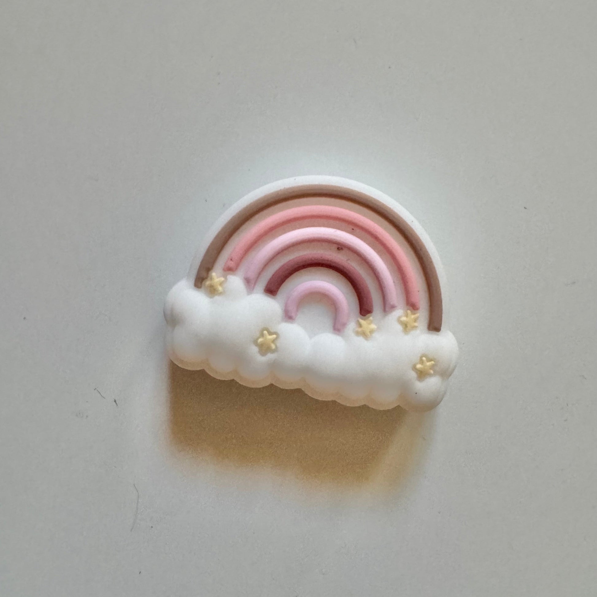 Decorative rainbow bead with clouds and stars on a light gray background