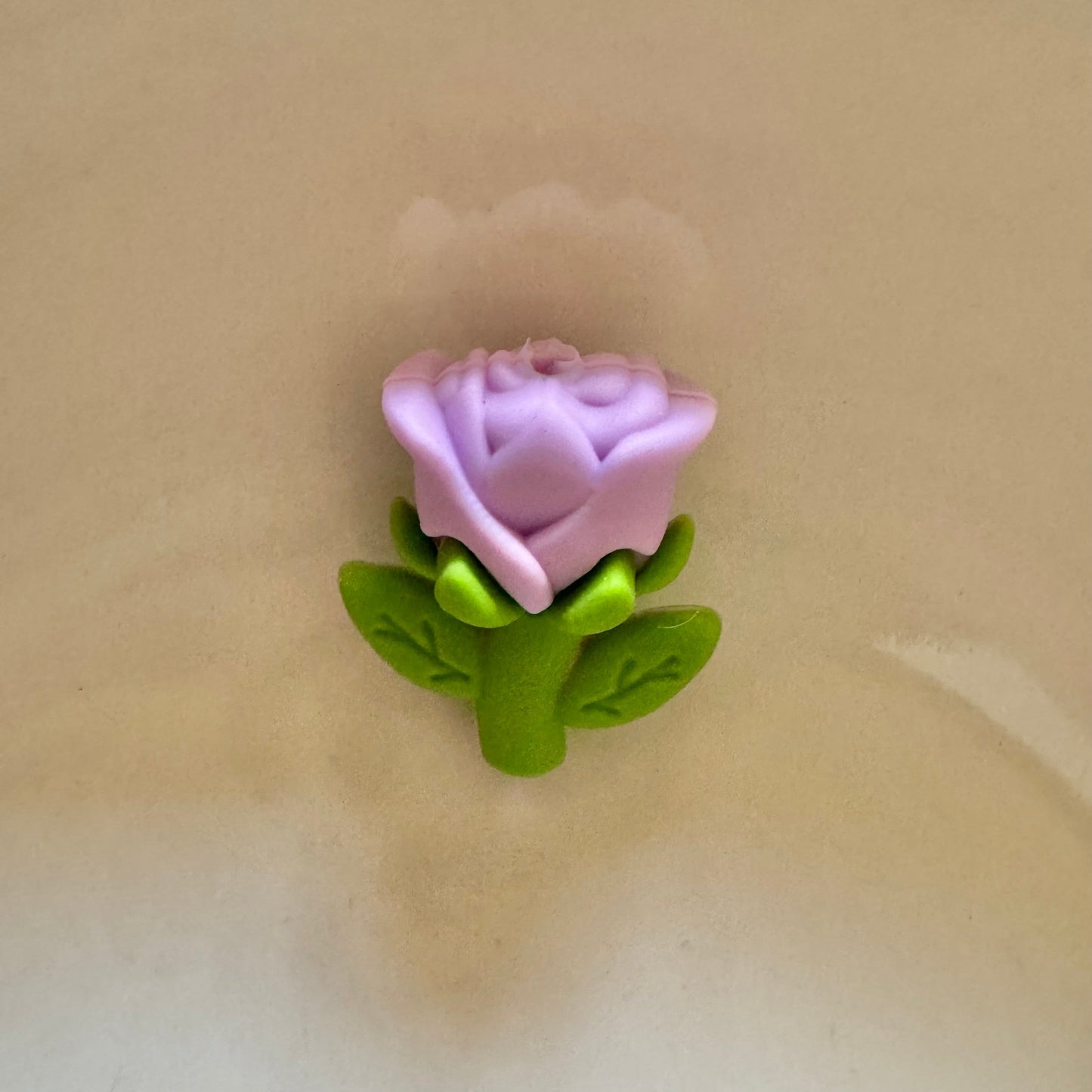 Purple rose with green leaves on a beige background