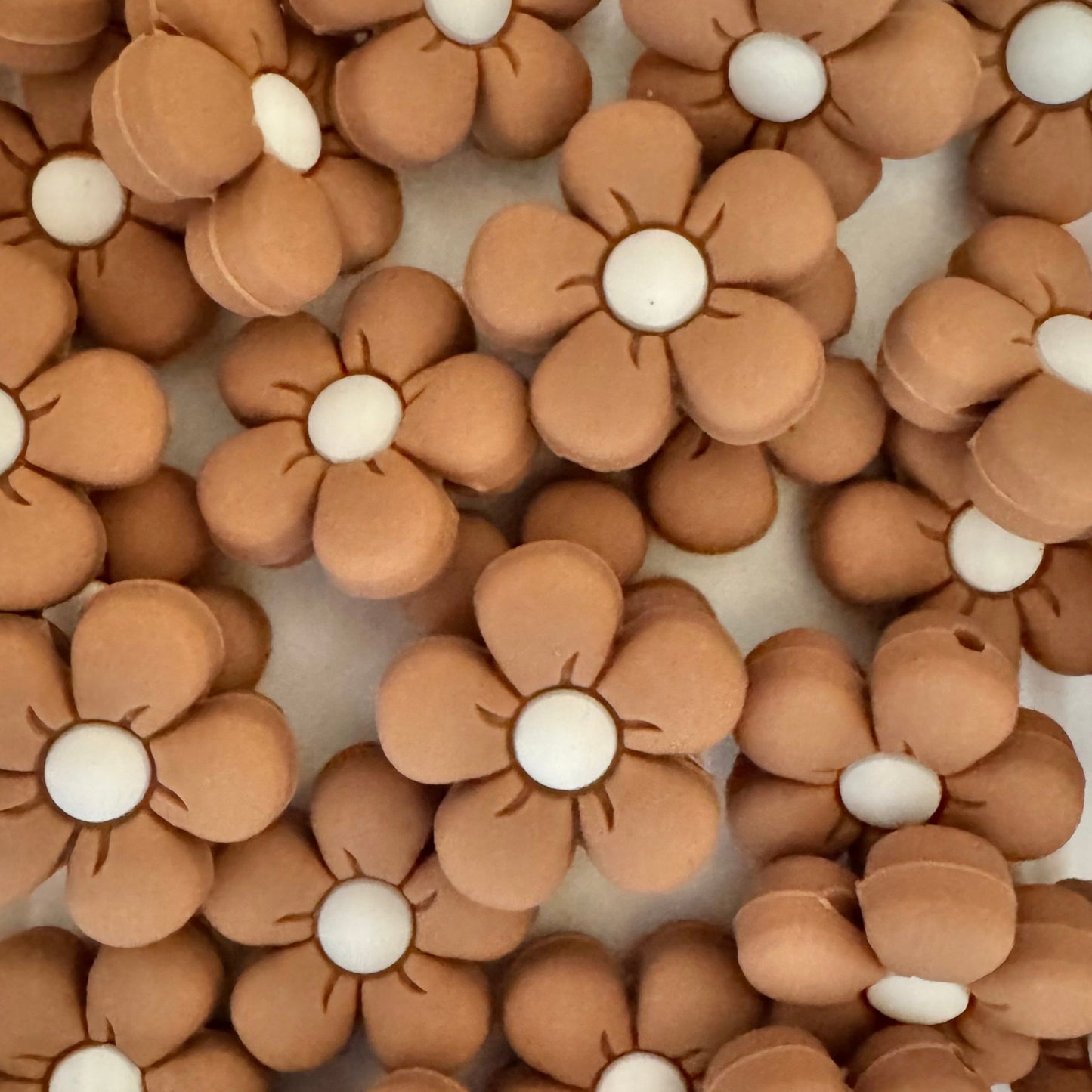 Brown clay flowers with white centers arranged on a white background