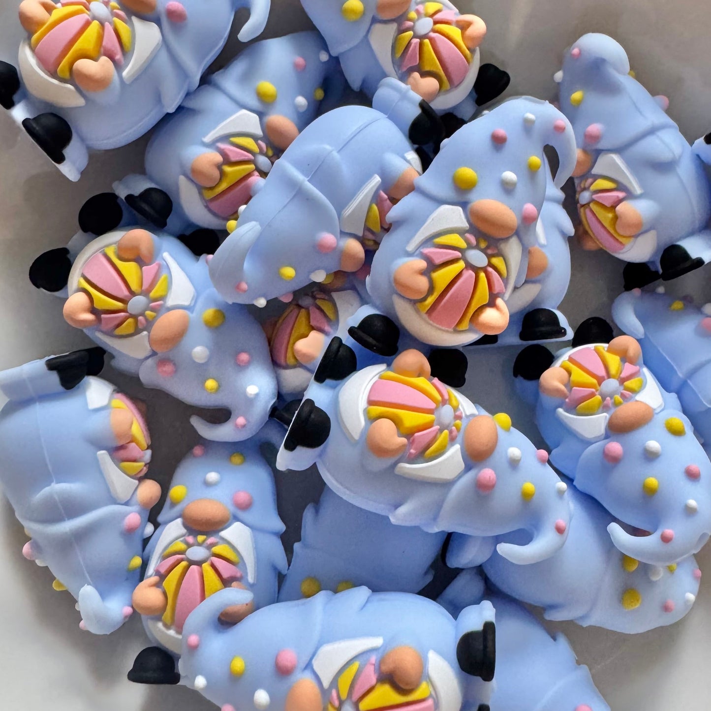 Collection of blue cat-shaped candies with colorful decorations on a white surface