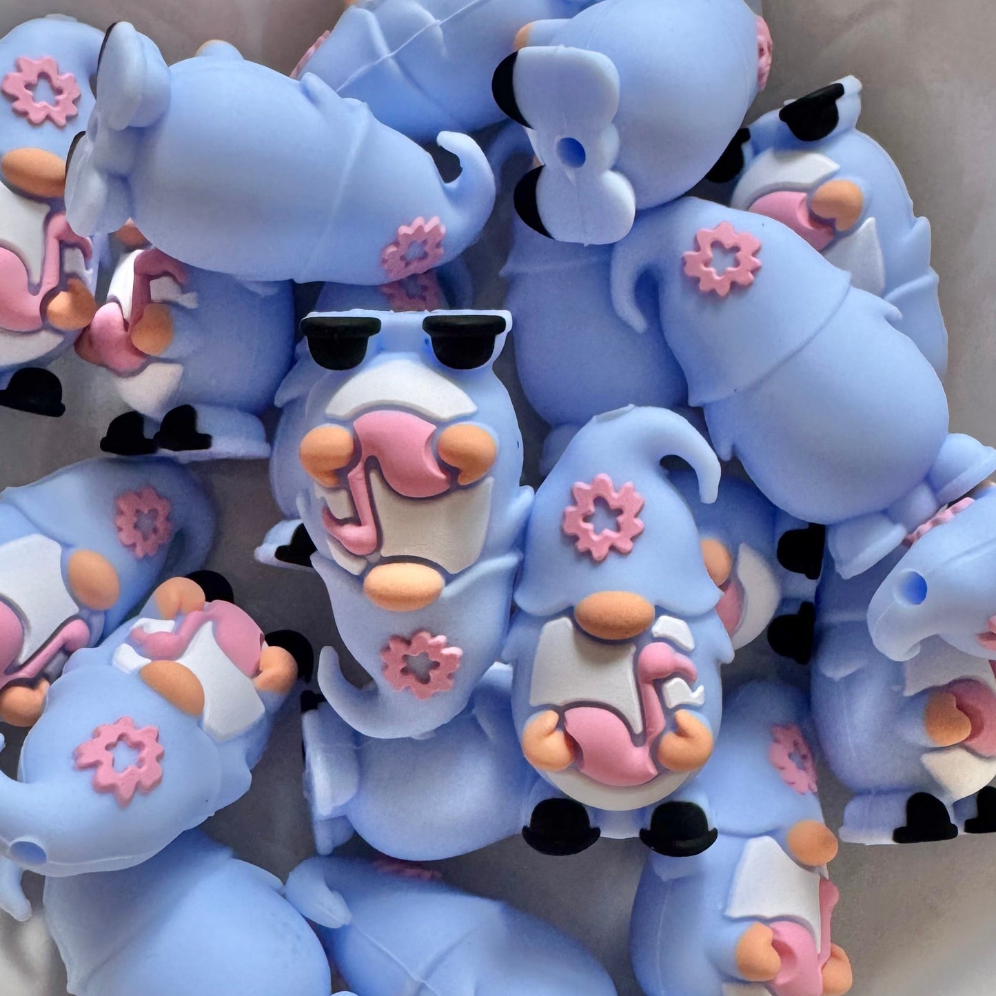 Collection of blue cartoonish animal figurines with sunglasses on a white surface