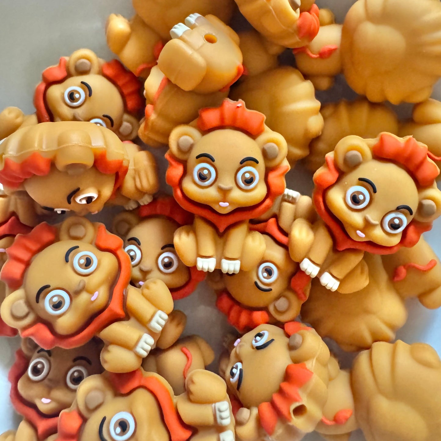 Collection of lion-shaped figurines with orange manes on a light background