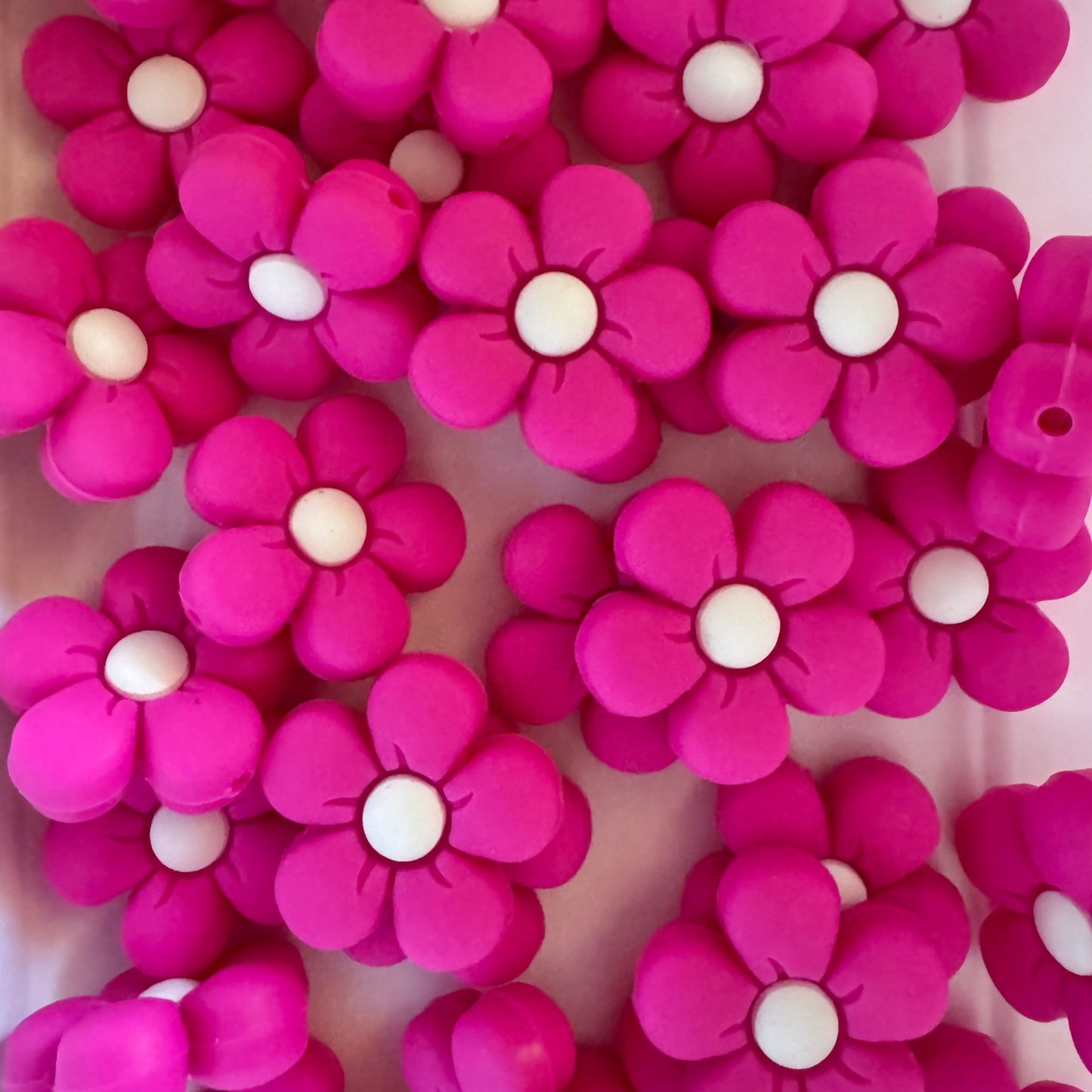 Pink flower-shaped beads with white centers on a white background