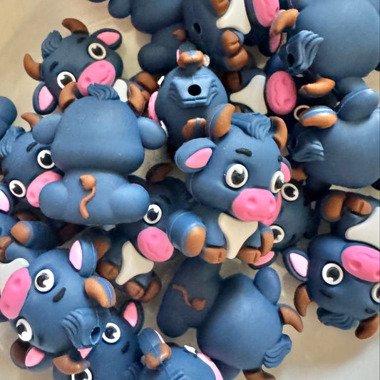 Collection of blue animal beads with pink accents on a white surface