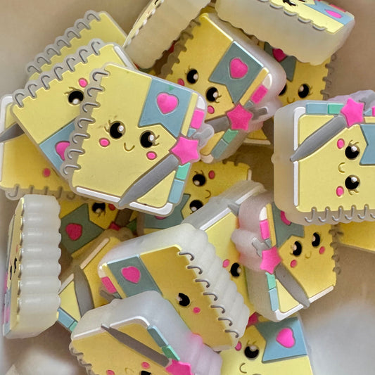 Stack of small yellow notebooks with cartoon faces on a white surface