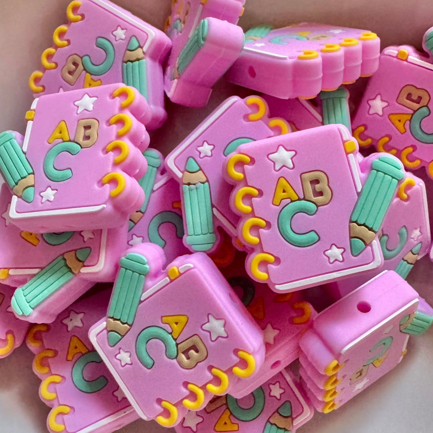 Pink bead with 'ABC' and colorful designs on a white surface