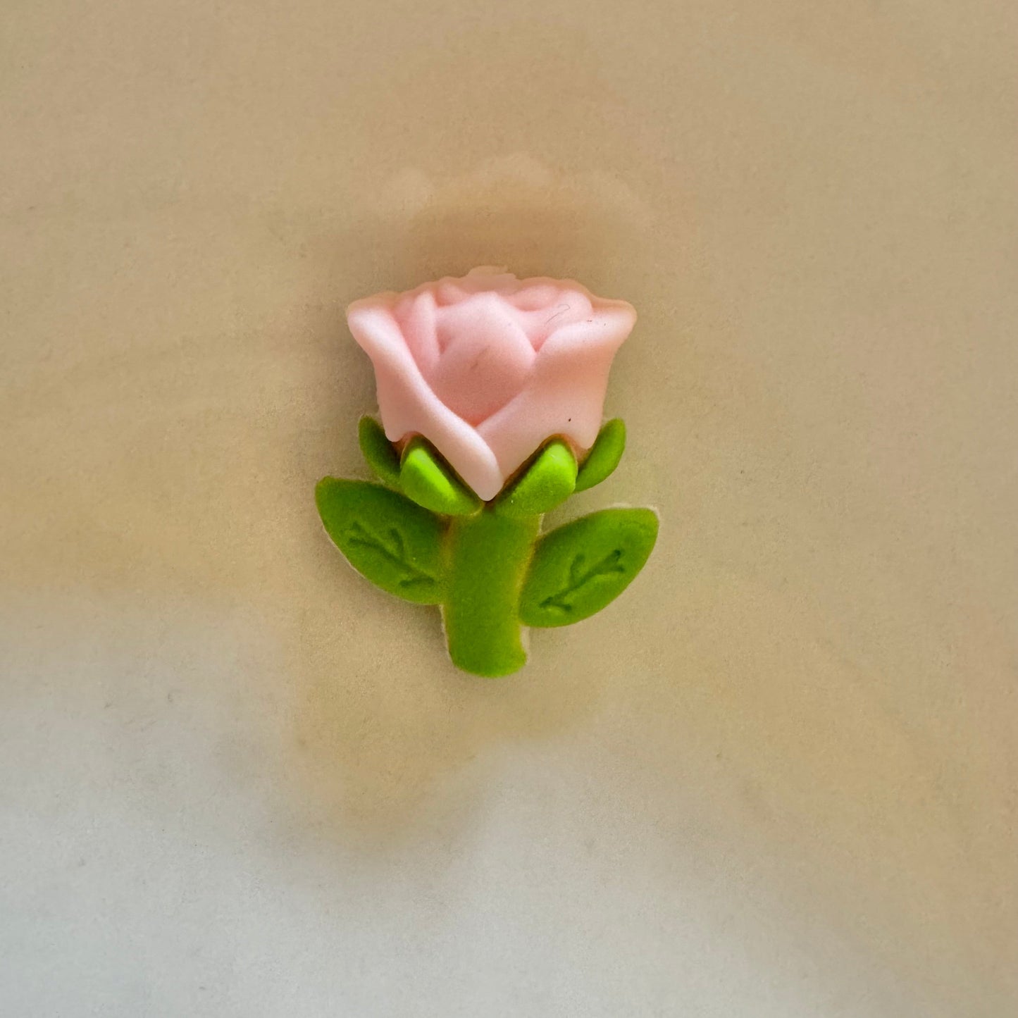 Pink rose with green leaves on a beige background