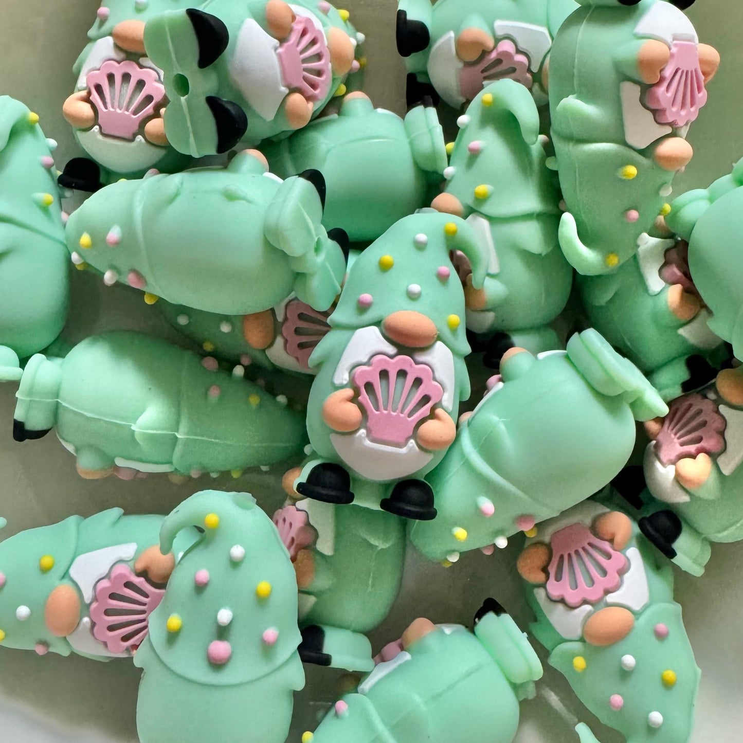 Green caterpillar-shaped candies with shell decorations on a white plate