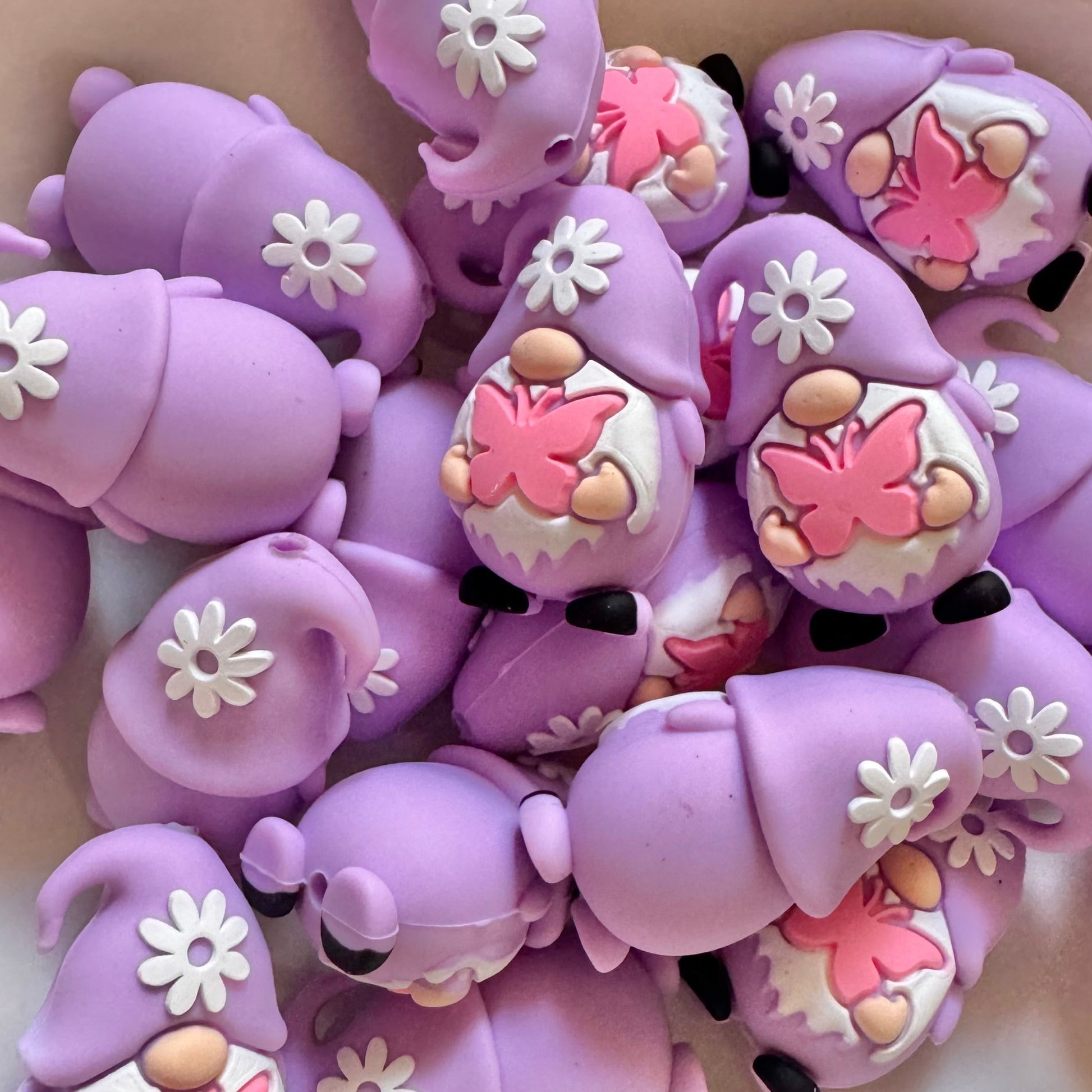Purple gnome figurines with pink butterfly designs on a light background