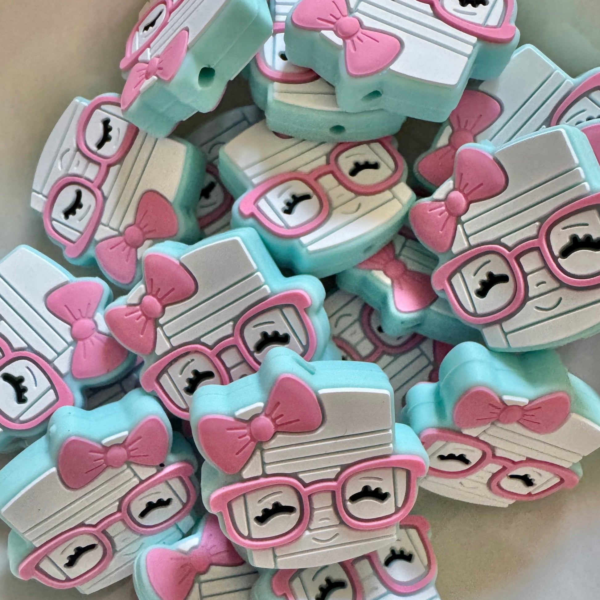 Collection of decorative beads with cartoon faces wearing glasses and bows.