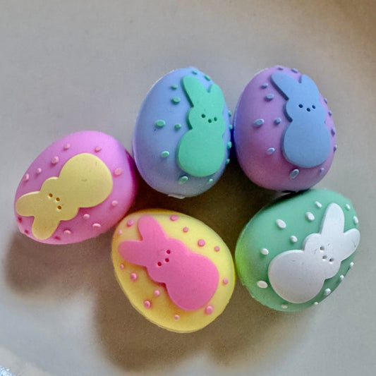Colorful Easter egg-shaped candies with rabbit designs on a light background