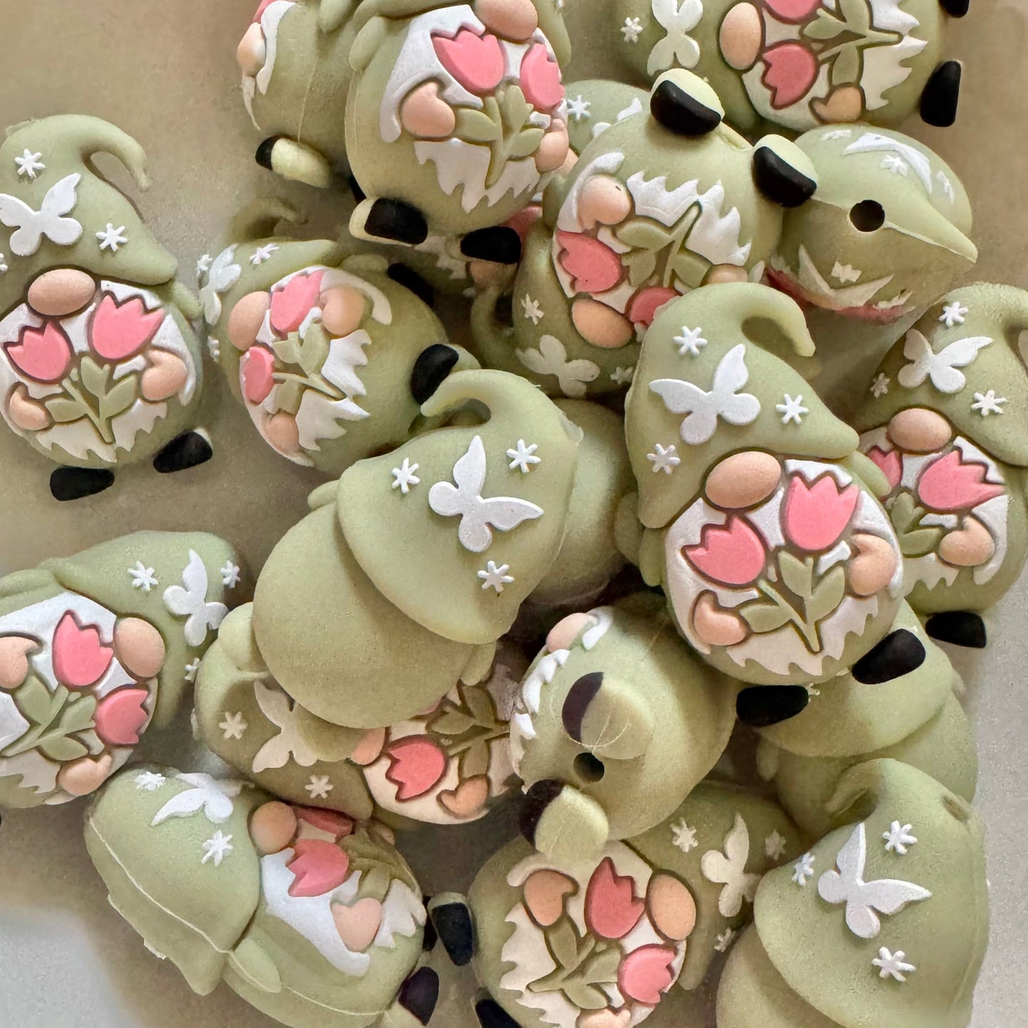 Decorative green gnomes with floral designs on a white plate